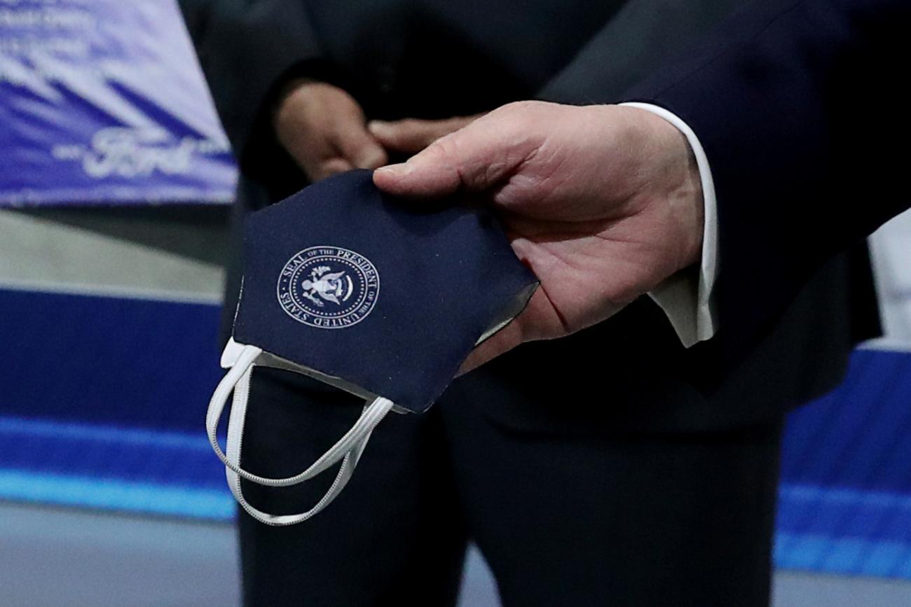 Photo shows a pair of hands holding the mask, which is printed with the seal of the White House. 