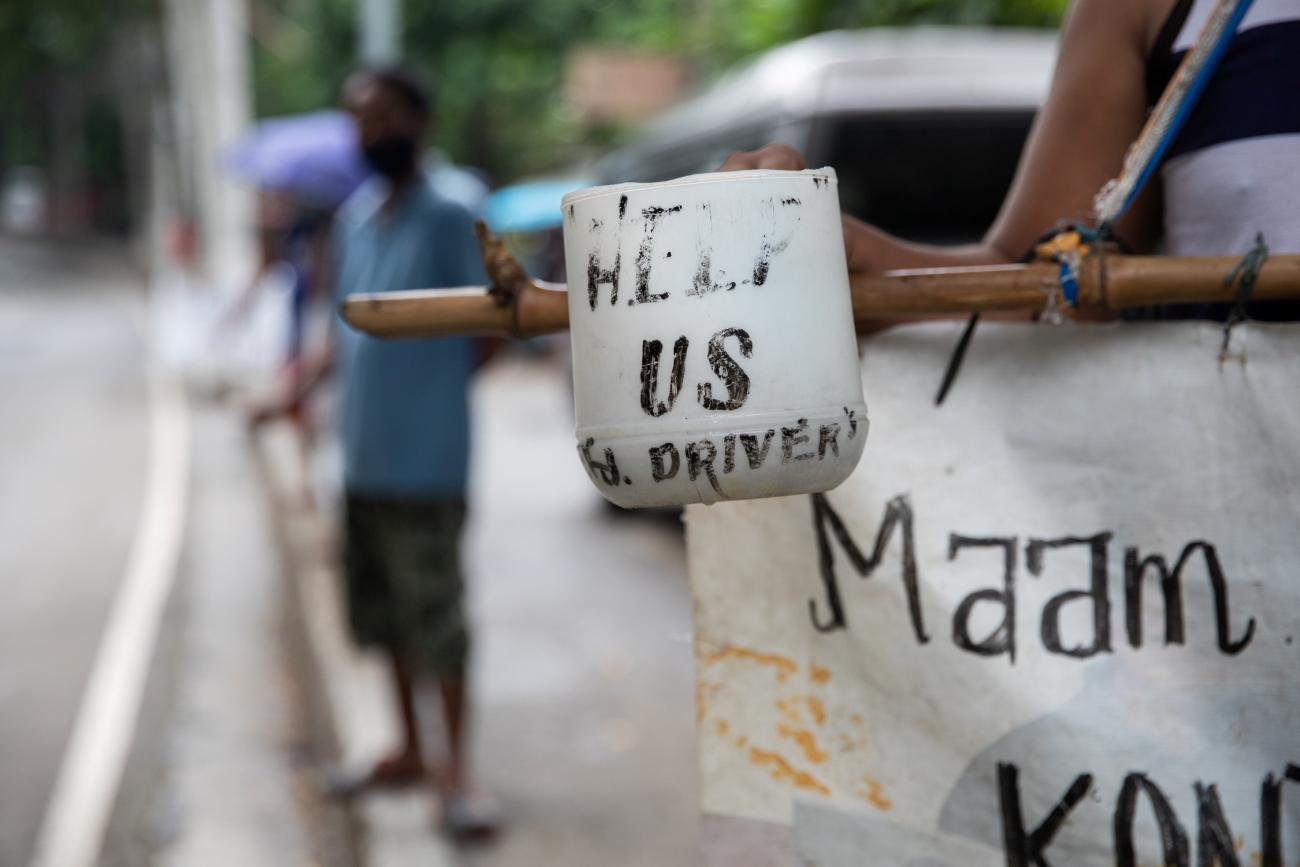 A plastic cup with the words "help us" is held by a jeepney driver who lost his livelihood amid the coronavirus disease outbreak, on a roadside in Quezon City, Metro Manila, Philippines on July 30, 2020.