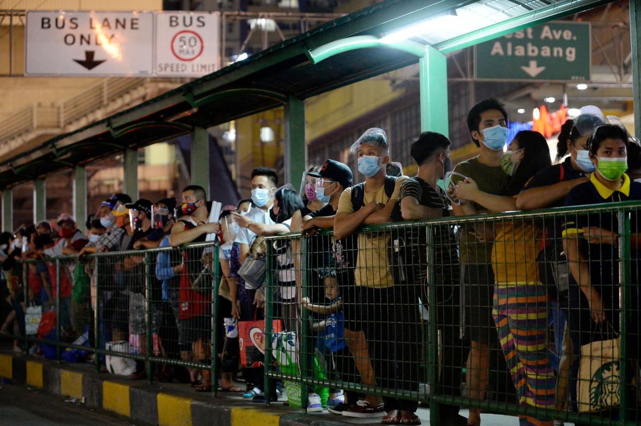  People wearing face masks and face shields as protection against the coronavirus disease queue at a bus stop, in Quezon City, Metro Manila, Philippines on December 23, 2020.