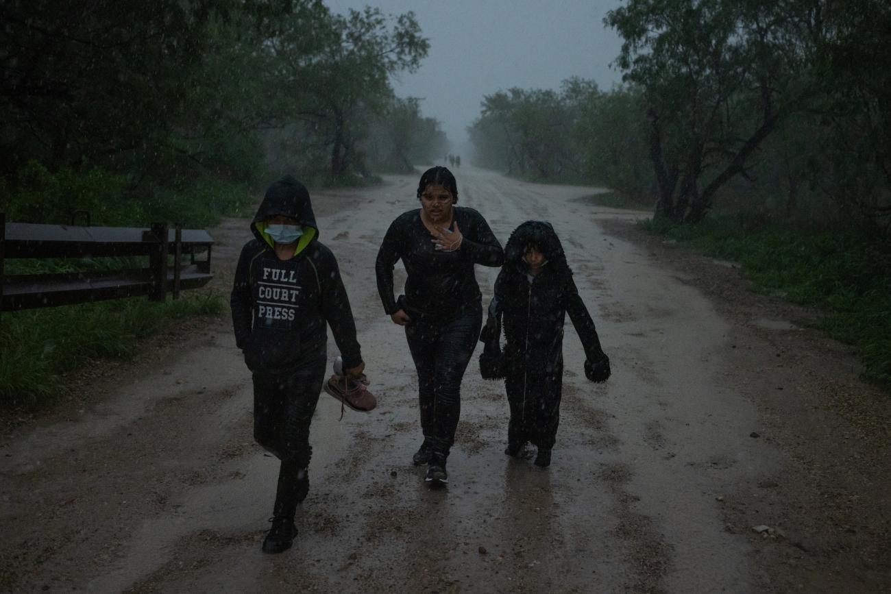 Asylum-seeking unaccompanied migrant children from Central America walk in heavy rainfall after crossing the Rio Grande river.