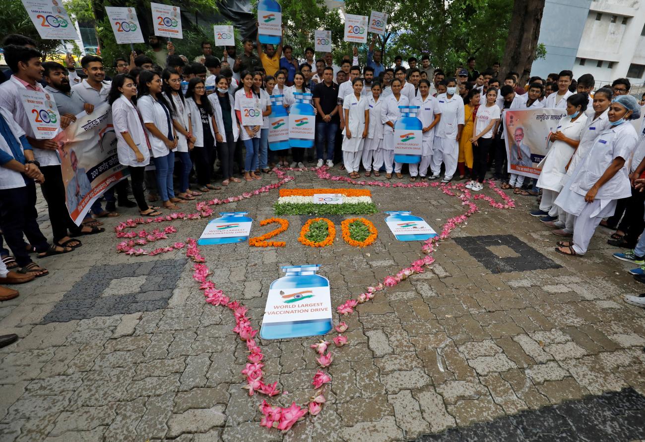 Medical staff and students hold placards as they stand around a formation to celebrate India administering 2 billion doses of vaccinations against COVID-19.