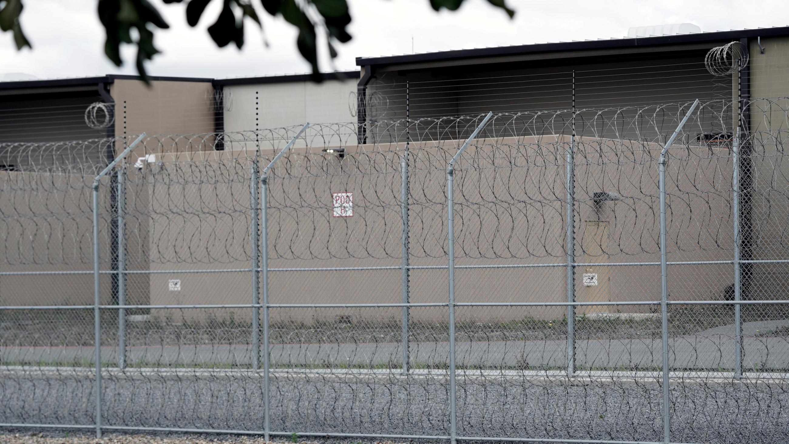 The photo shows a lockup from outside its perimeter barbed wire fence. 