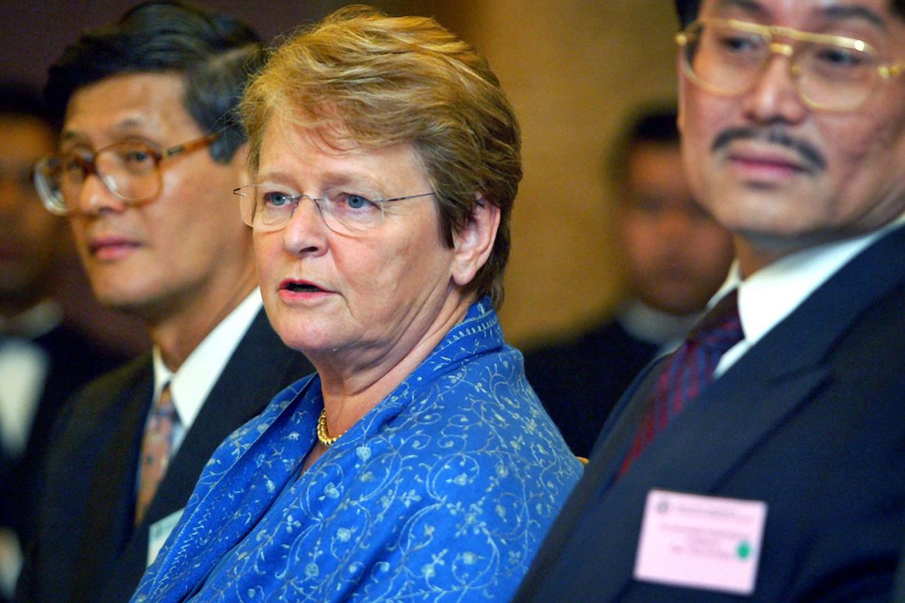 The three speakers are seated, presumably in front of an array of microphones, cameras, and reporters who are out of the frame. 