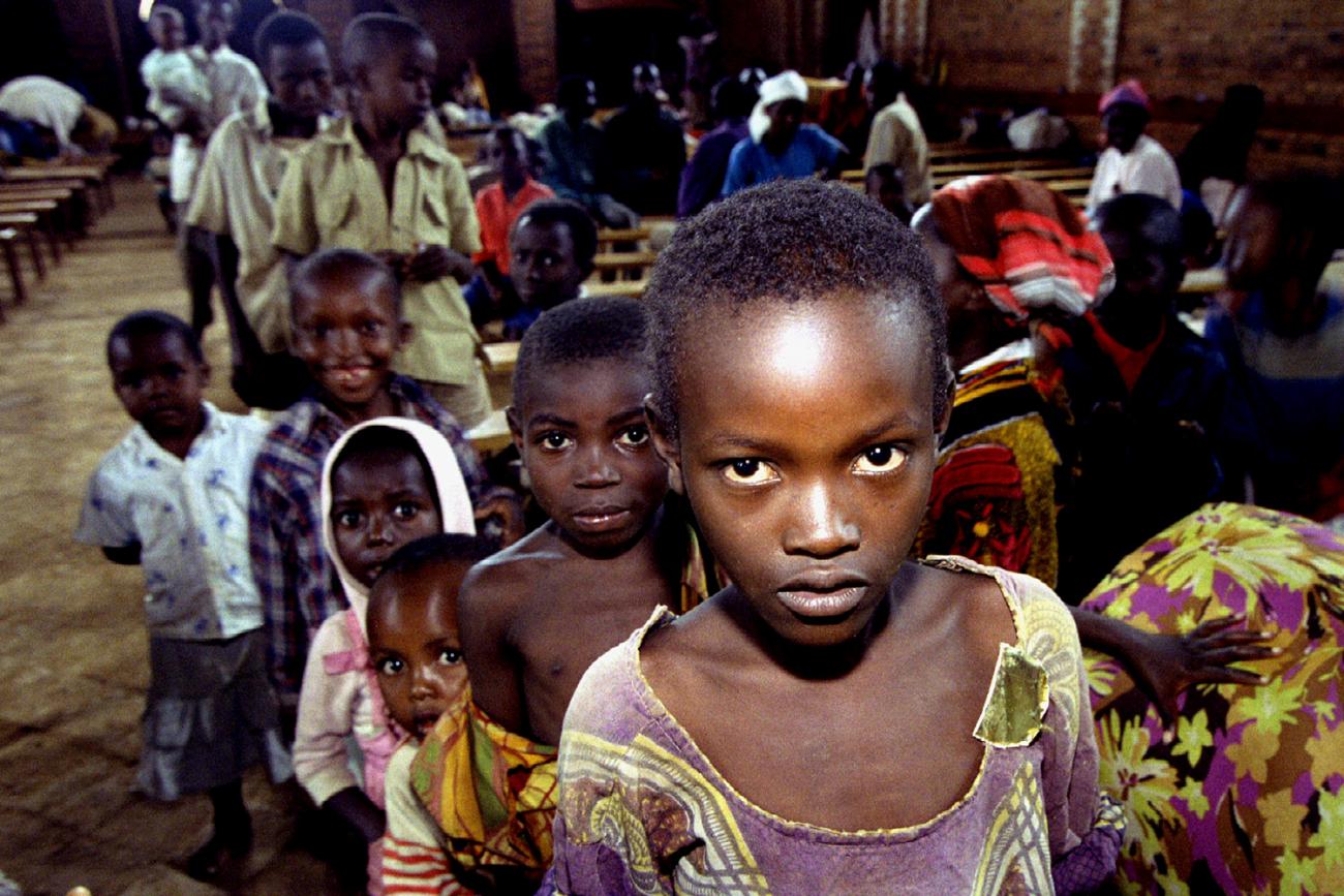 This is a powerful photo filled with children war refugees in a line awaiting food. The child in front is looking directly at the camera with a haunting expression. 