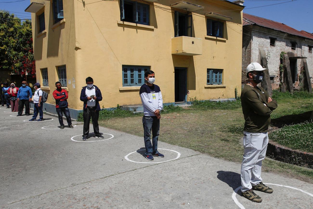 photo shows people in a line standing in painted circles. 