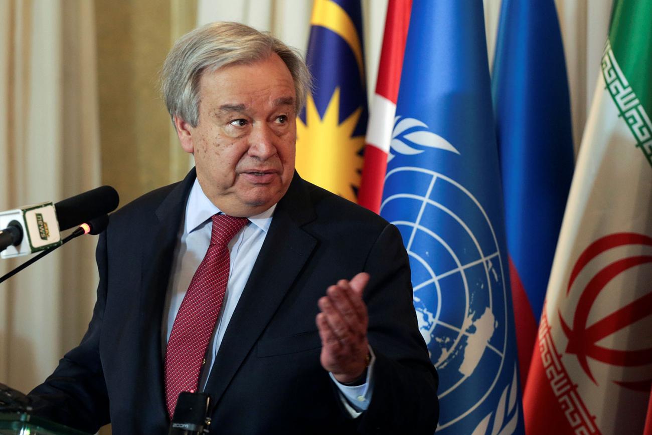 The photo shows the Secretary-General standing at a podium speaking into a microphone. 