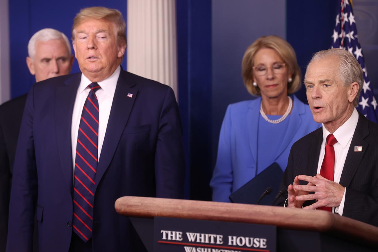 The photo shows several officials gathered around a podium during a press conference. 