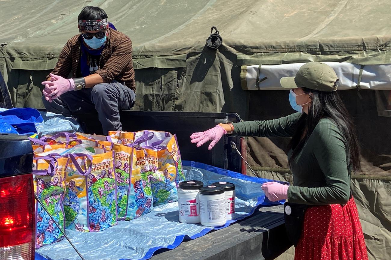 Picture shows two people and a pickup truck filled with supplies. 