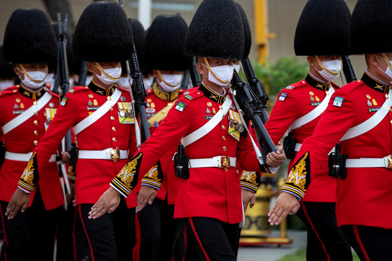 The photo shows the honor guard clad in bright red military coats on parade in lock step. 