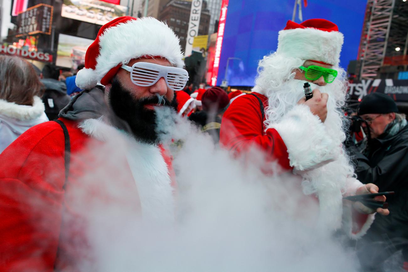 The photo shows several santas in a row smoking on vapor devices. 