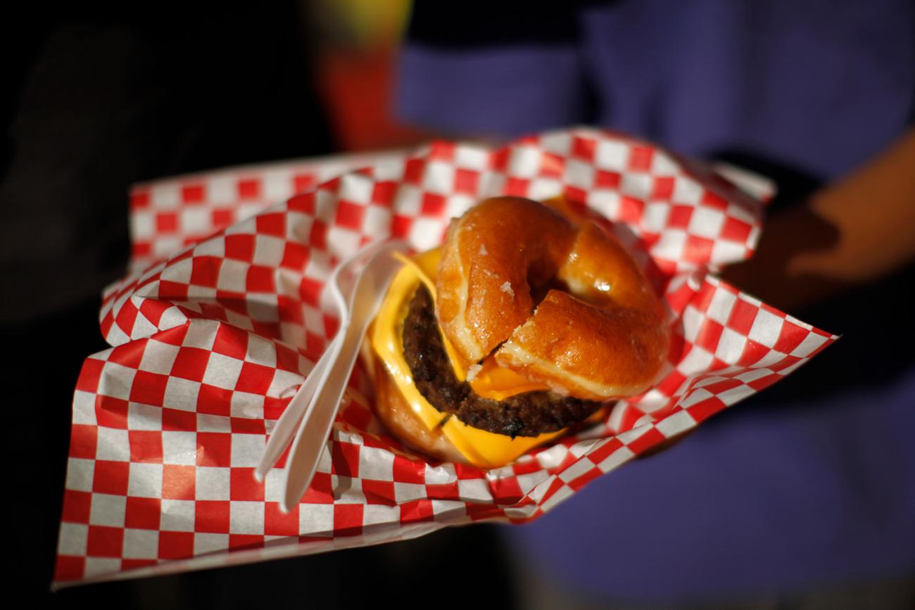 The photo shows a huge burger with cheese in between two glazed donuts. 