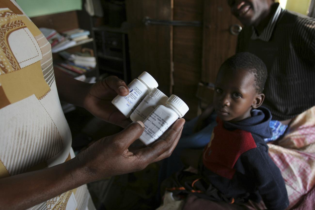 A woman holds bottles of daily anti-retroviral drugs and vitamin supplements as her husband and son look on in their one-room home on the outskirts of Botswana'a capital Gaborone, on November 27, 2006.