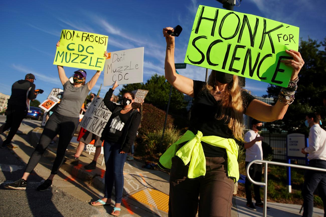 In September 2020, people held up bright green signs saying "Honk for Science" as they protested former U.S. President Donald J. Trump’s COVID policies during a rally outside the Centers for Disease Control and Prevention in Atlanta, Georgia.