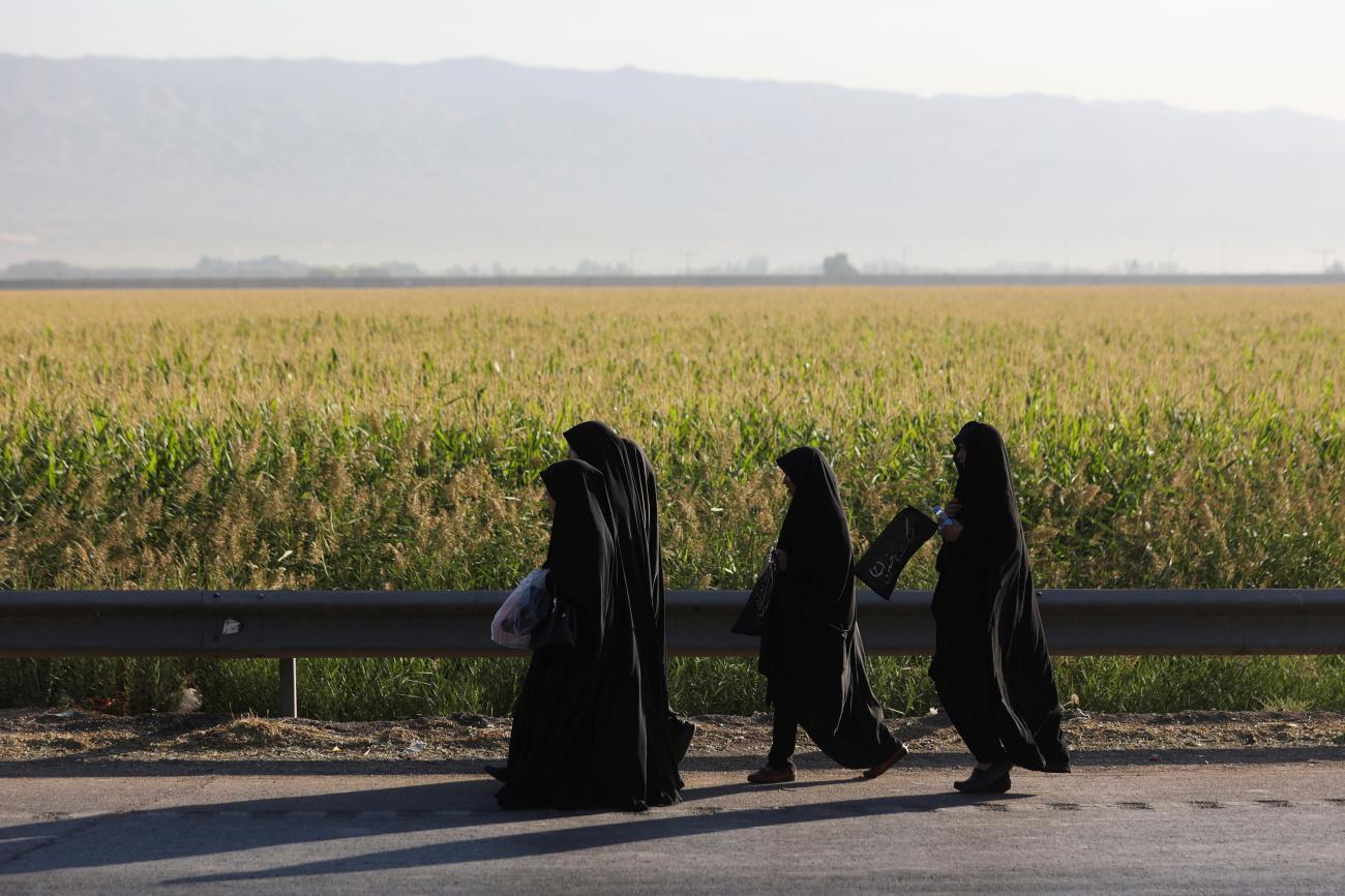 Women walk by a green field and hold flags to commemorate Arbaeen, a religious holiday, in southern Tehran, Iran September 17, 2022. 