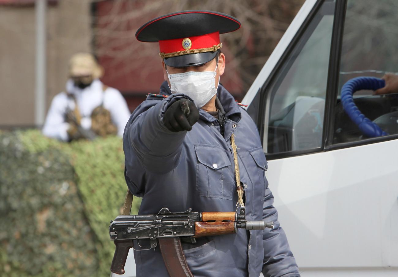 A Kyrgyz law enforcement officer gestures while verifying drivers and passengers' documents at a check point during a COVID-19 curfew, near Bishkek, Kyrgyzstan, on March 26, 2020. 