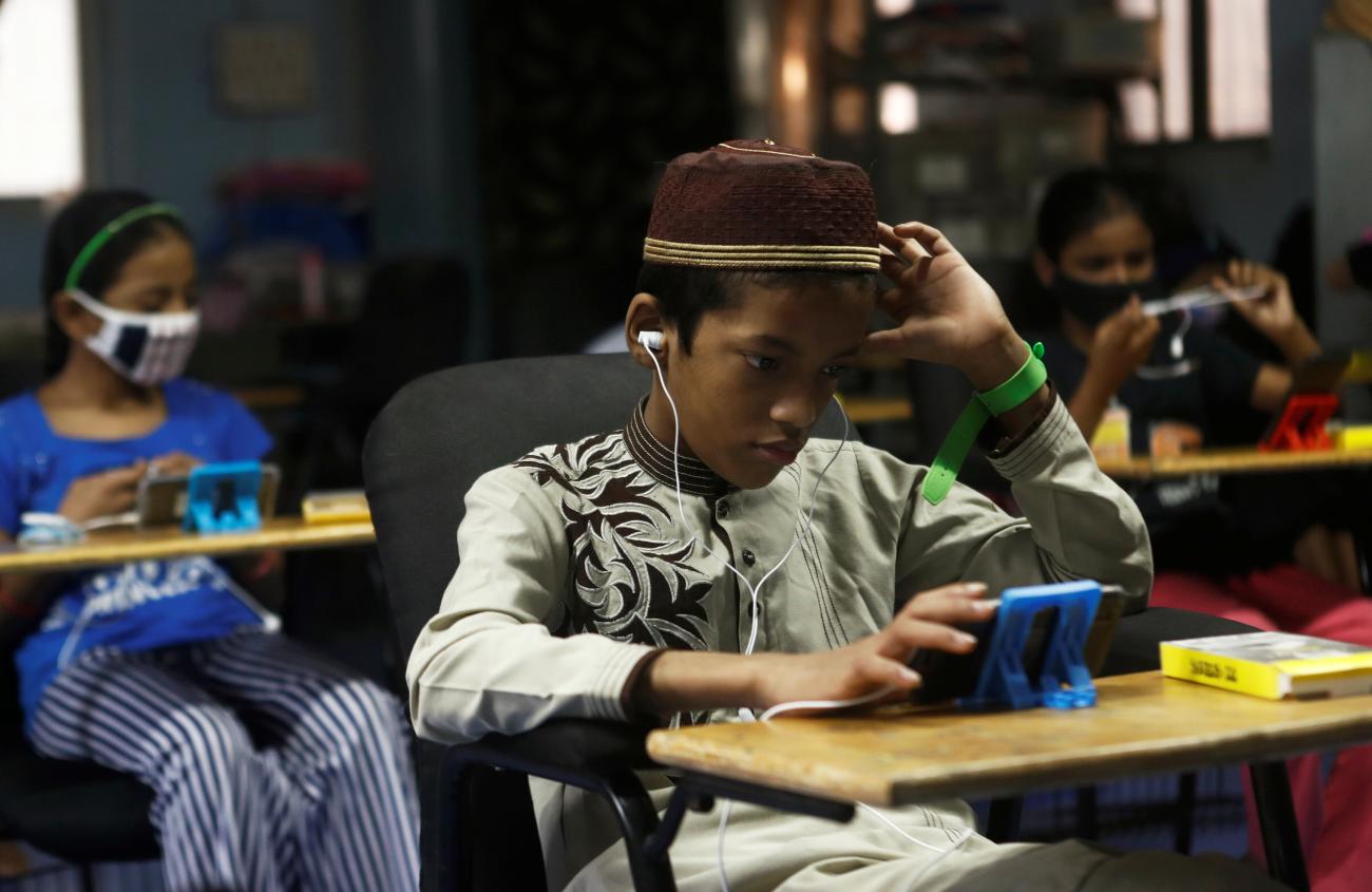 Children watch online lectures on mobile phones inside a digital mobile education library, amid the spread of COVID-19.