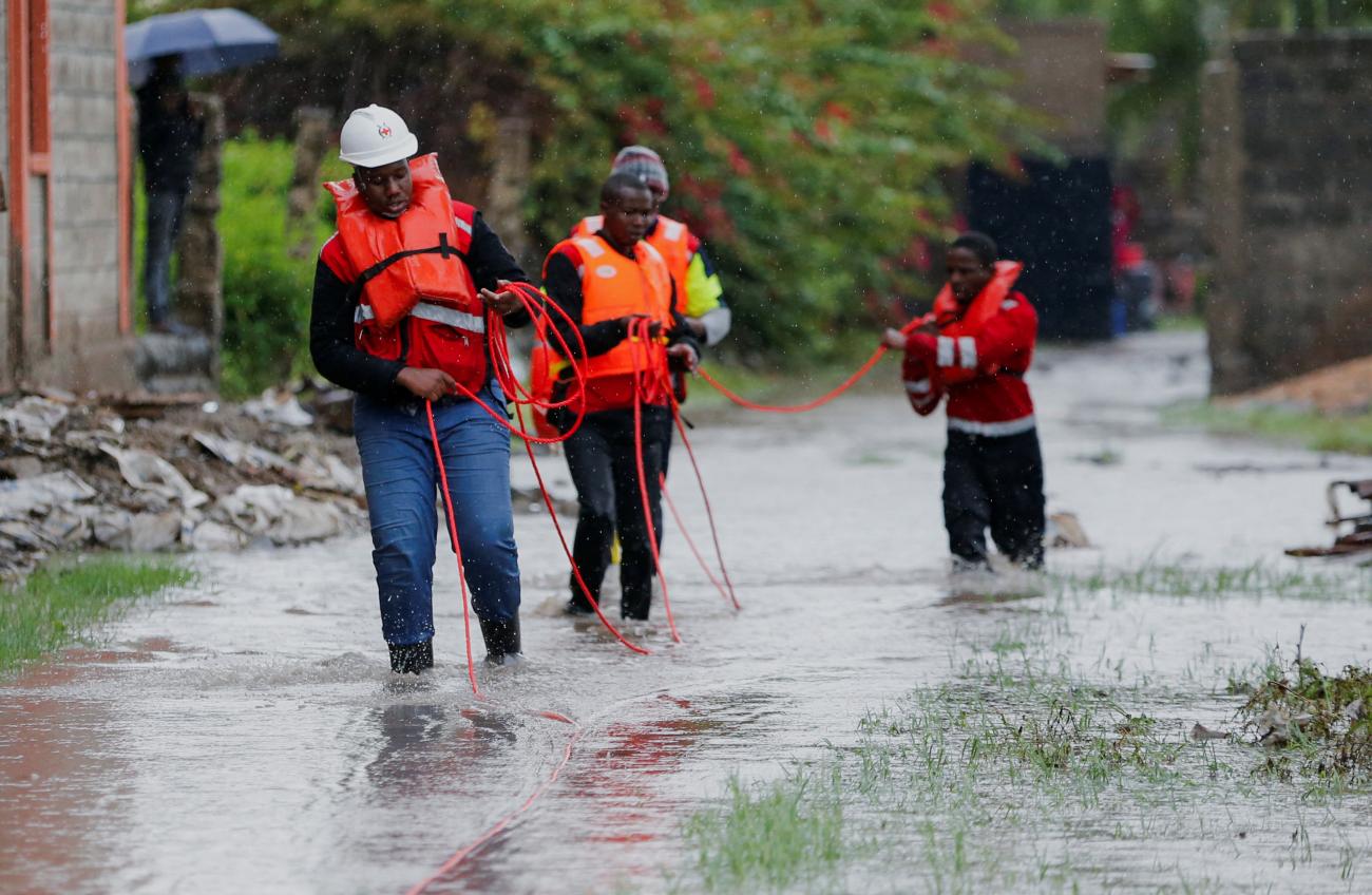 Kenya Red Cross members hold on to a safety rope as they wade through flood waters to assess and rescue residents trapped in their homes