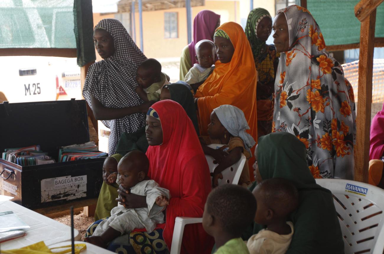 Women with their children wait to see doctors at a clinic.