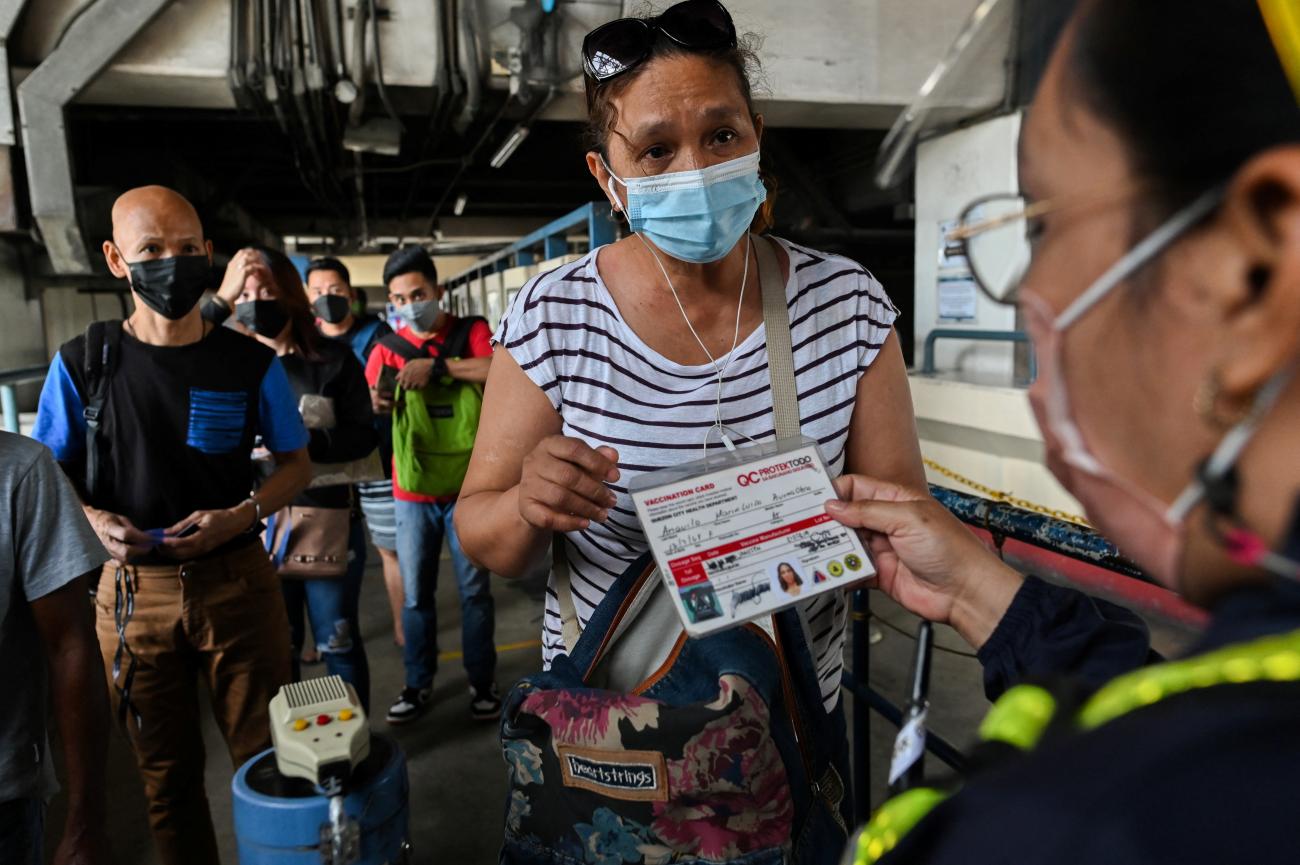 A woman wearing a face mask as protection against COVID-19 presents her vaccination card at a train station in Quezon City, Metro Manila, Philippines, January 17, 2022.