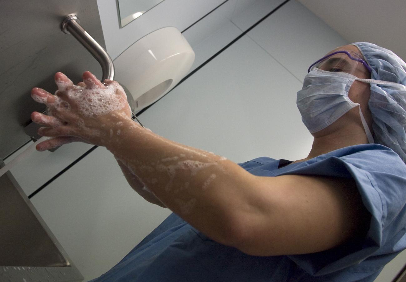 A surgery nurse washes her hands before a procedure on a patient with methicillin-resistant Staphylococcus aureus.