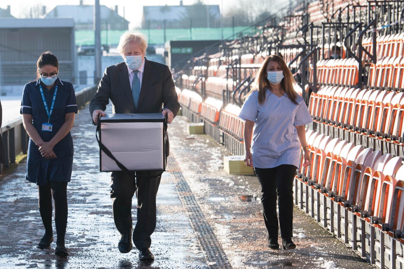 Prime Minister Boris Johnson loads doses of the Oxford/AstraZeneca COVID-19 vaccine for mobile distribution at Barnet FC's ground, in London, England, on January 25, 2021.