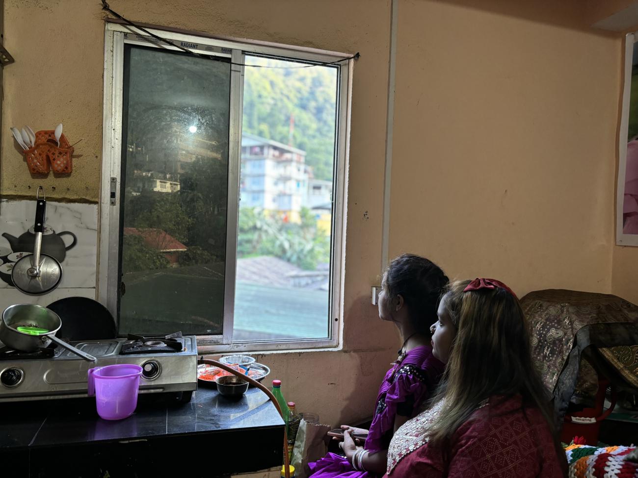 Neelam and Preeti look outside their kitchen window.