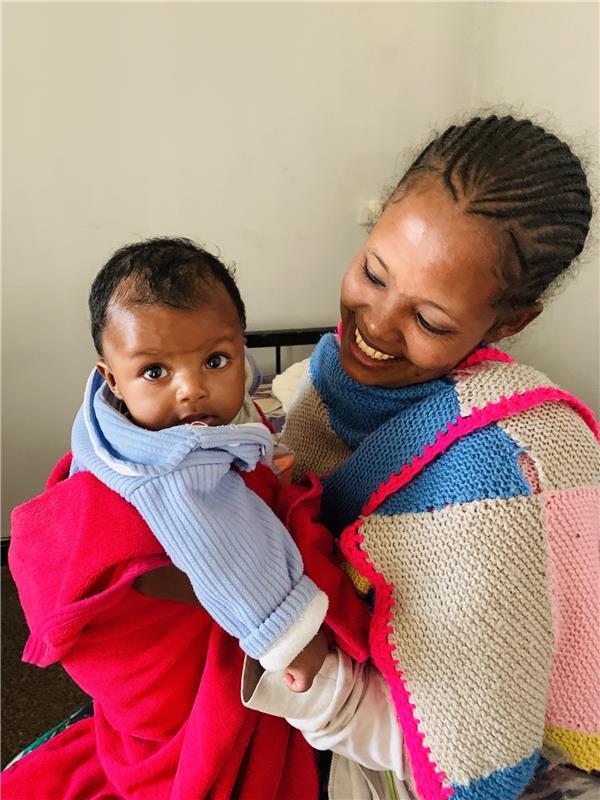 A woman holds her child as many women like Nigisty are now reclaiming their right to safe births in the aftermath of the war.