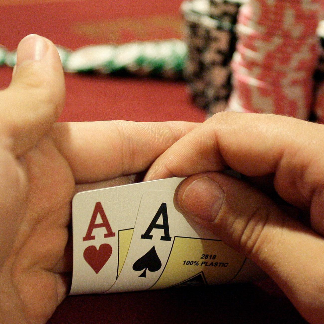 A player checks his cards during the finals of the Russian Masters Poker Cup at the Azov-City, Russia, gambling zone, south of Russia's southern city of Rostov-on-Don, on September 23, 2010. Photo shows a pair of hands holding up the corners of two cards to reveal a pair of aces. A large stack of chips is in the background. REUTERS/Vladimir Konstantinov 