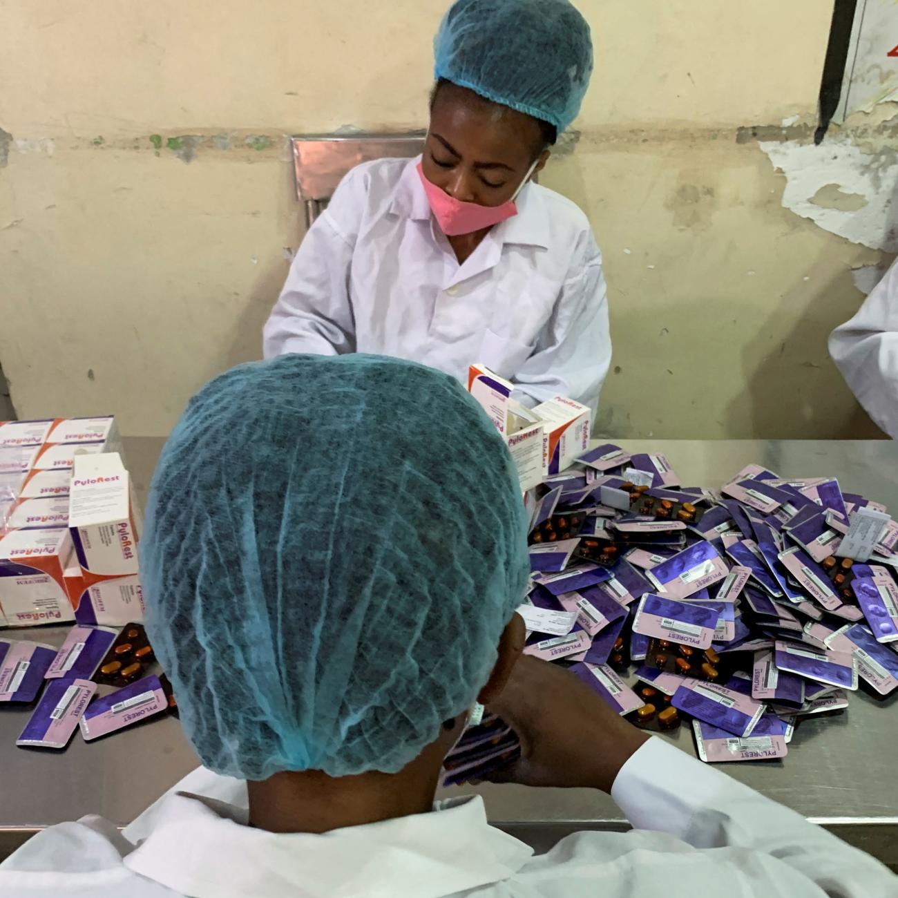 Workers at Biofem Industries processing facility stick authentication labels on drugs.