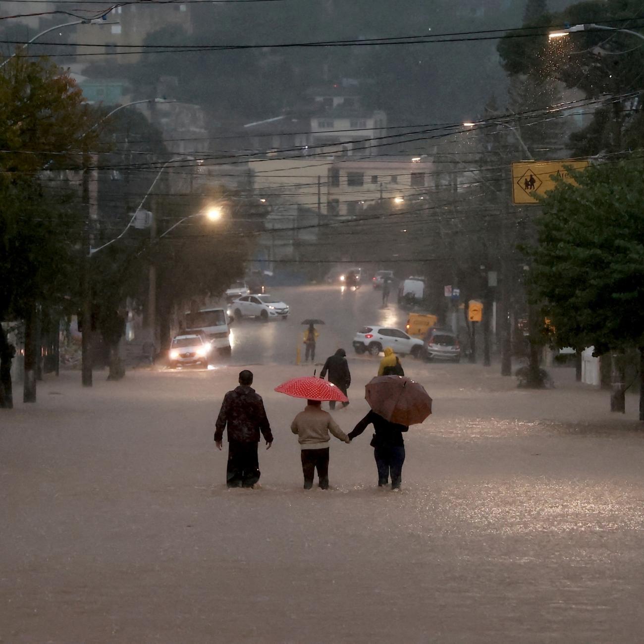 People walk in a flooded area in the Cavalhada neighborhood after heavy rains.