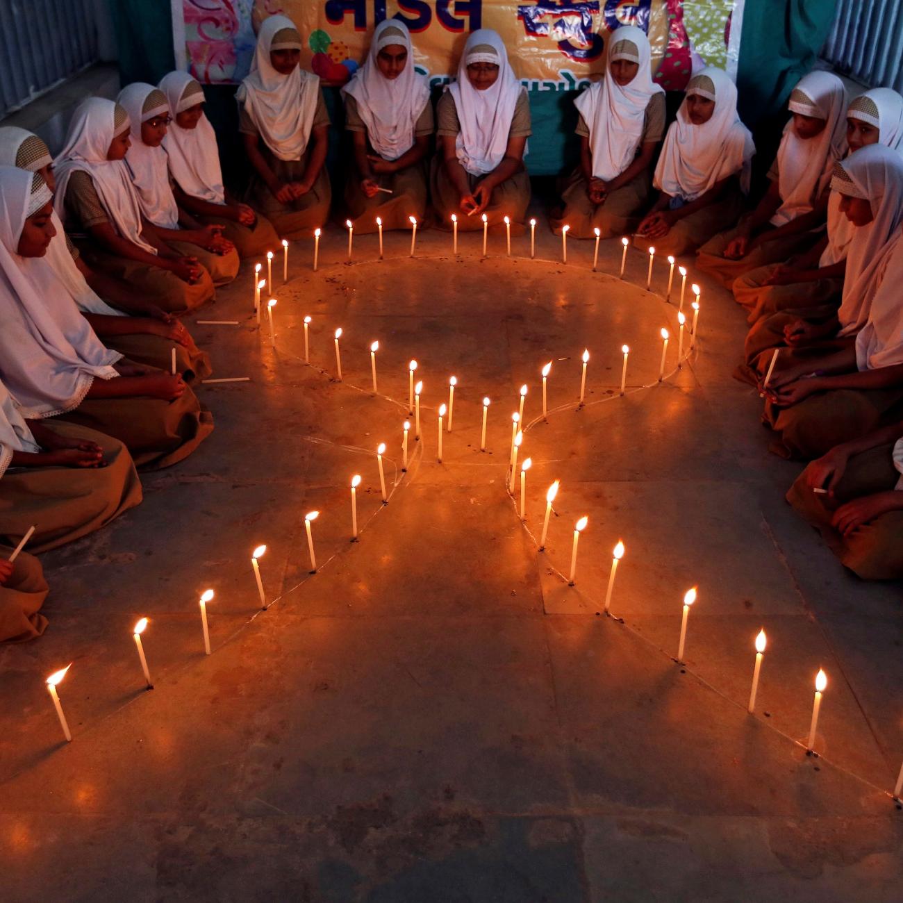 School girls light candles in the shape of a ribbon during a HIV/AIDS awareness campaign ahead of World Aids Day, in Ahmedabad, India November 30, 2016.