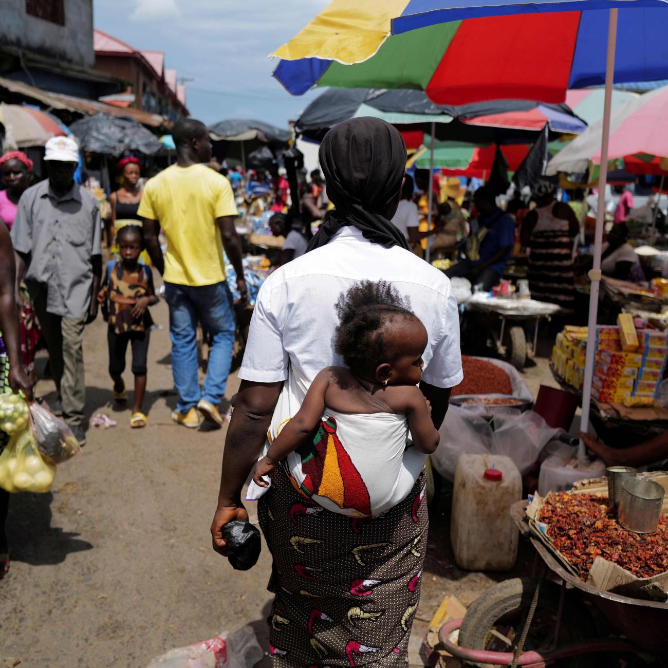 A woman carries her daughter as she walks through the Gobachop market.