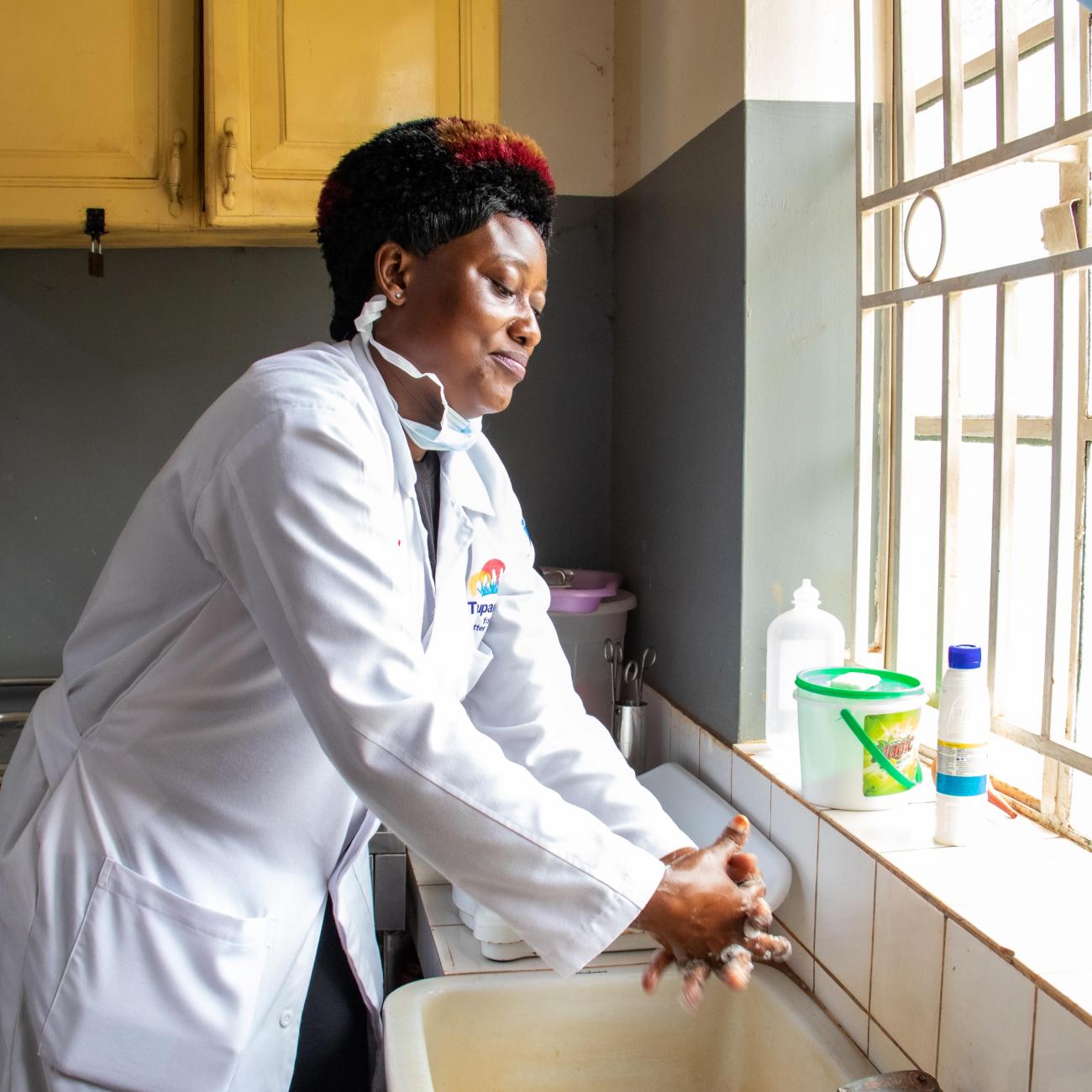 Ddungu Annet, a 39-year-old nursing officer, washes her hands in the labor ward before examining an expectant mother at Nabweru Health Center, Uganda. 