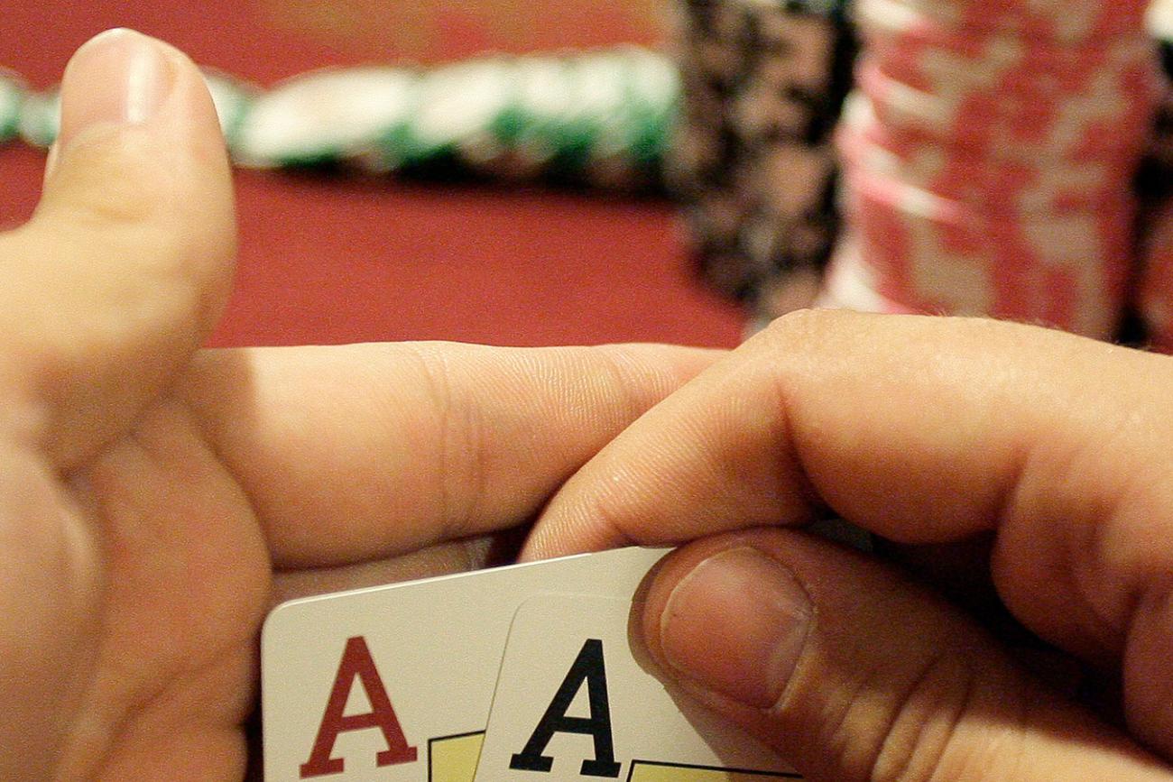 A player checks his cards during the finals of the Russian Masters Poker Cup at the Azov-City, Russia, gambling zone, south of Russia's southern city of Rostov-on-Don, on September 23, 2010. Photo shows a pair of hands holding up the corners of two cards to reveal a pair of aces. A large stack of chips is in the background. REUTERS/Vladimir Konstantinov 