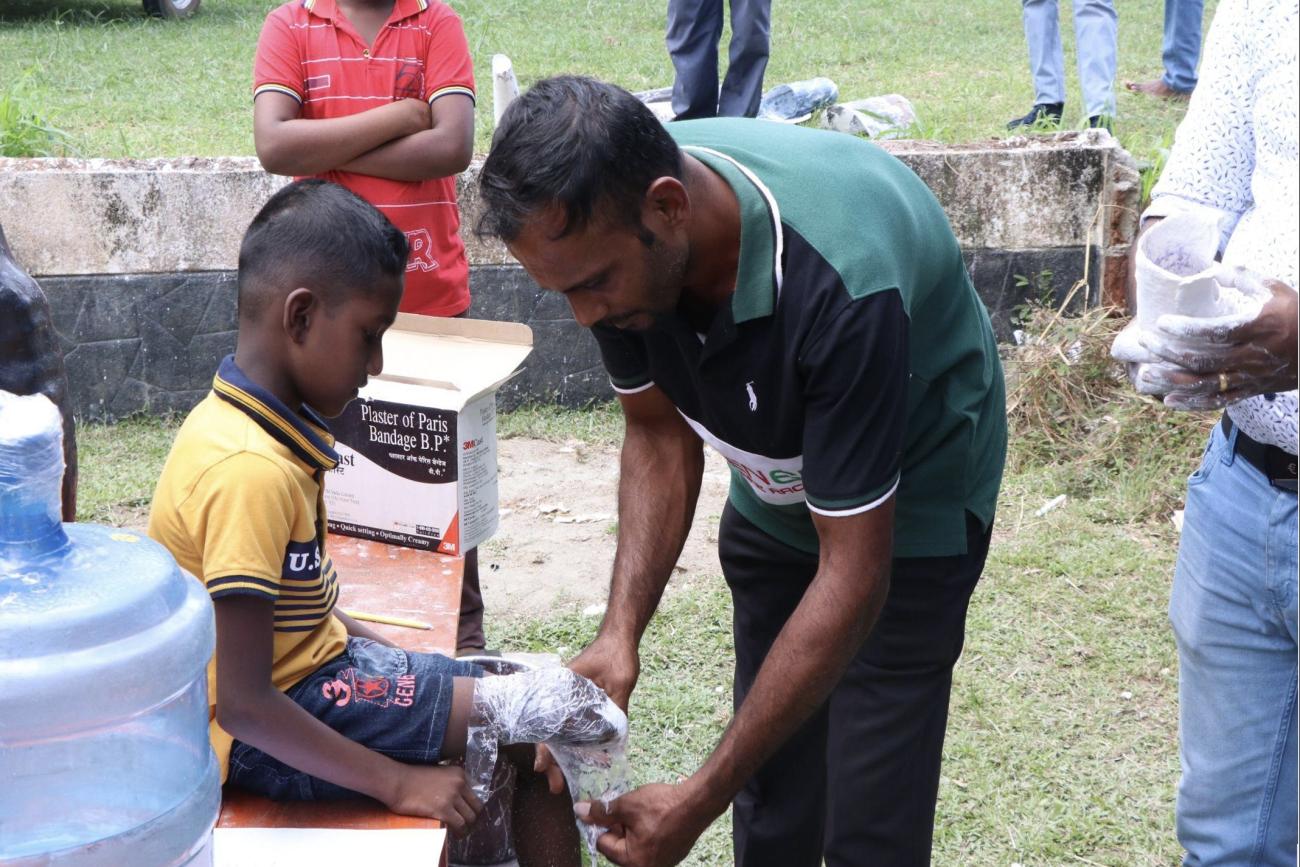 A man helps take a plaster cast of a young boy's limb.