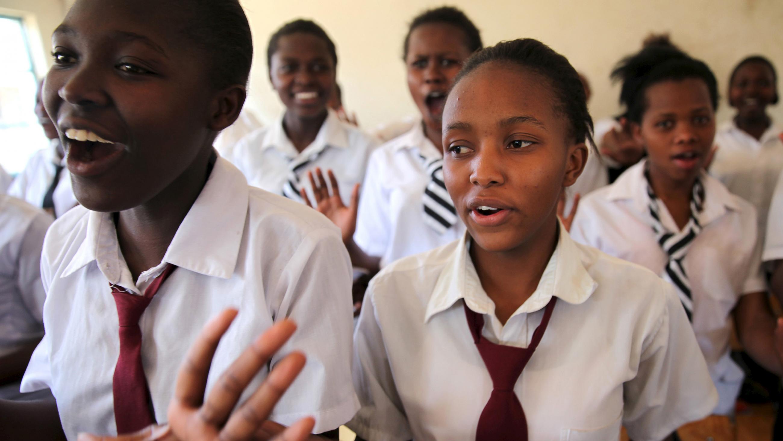 The girls are standing and gesturing with their hands and speaking out loud. 