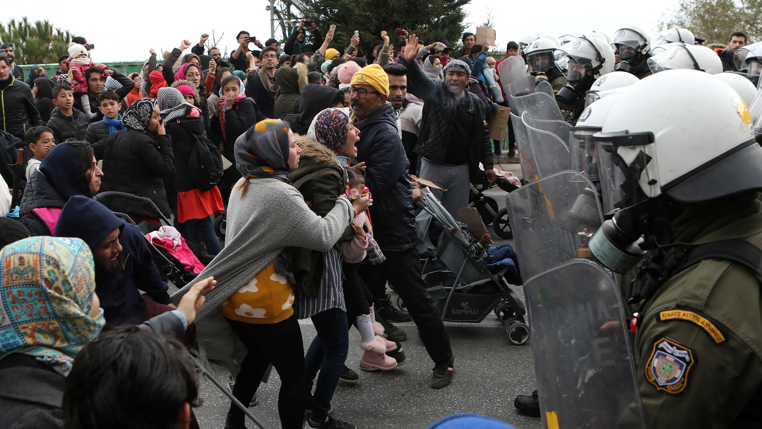 The photo shows a line of protesters clashing with a line of uniformed officers, some of whom hold plastic shields. 