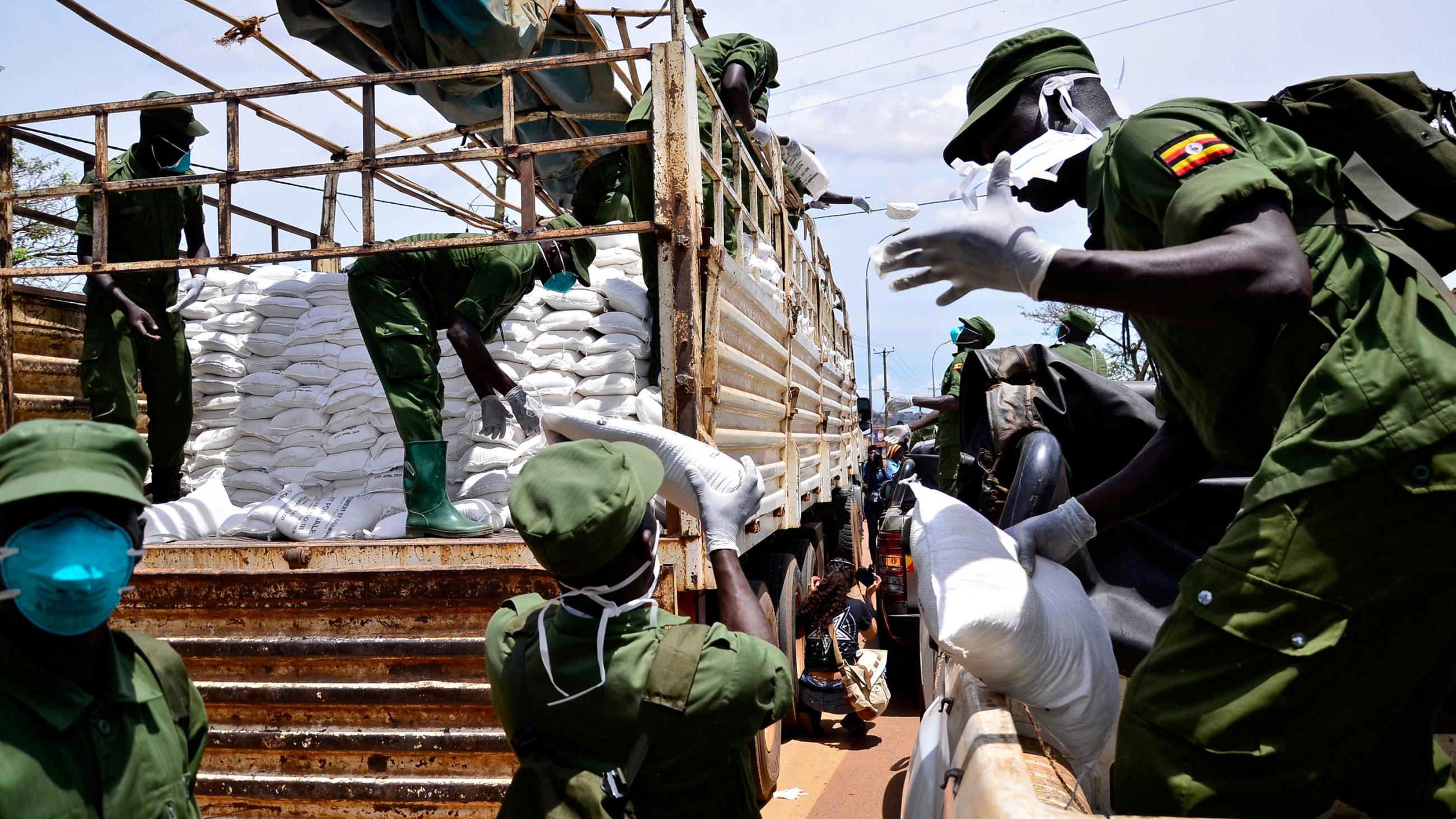 The photo shows uniformed soldiers unloading provisions from the back of a pickup truck. 