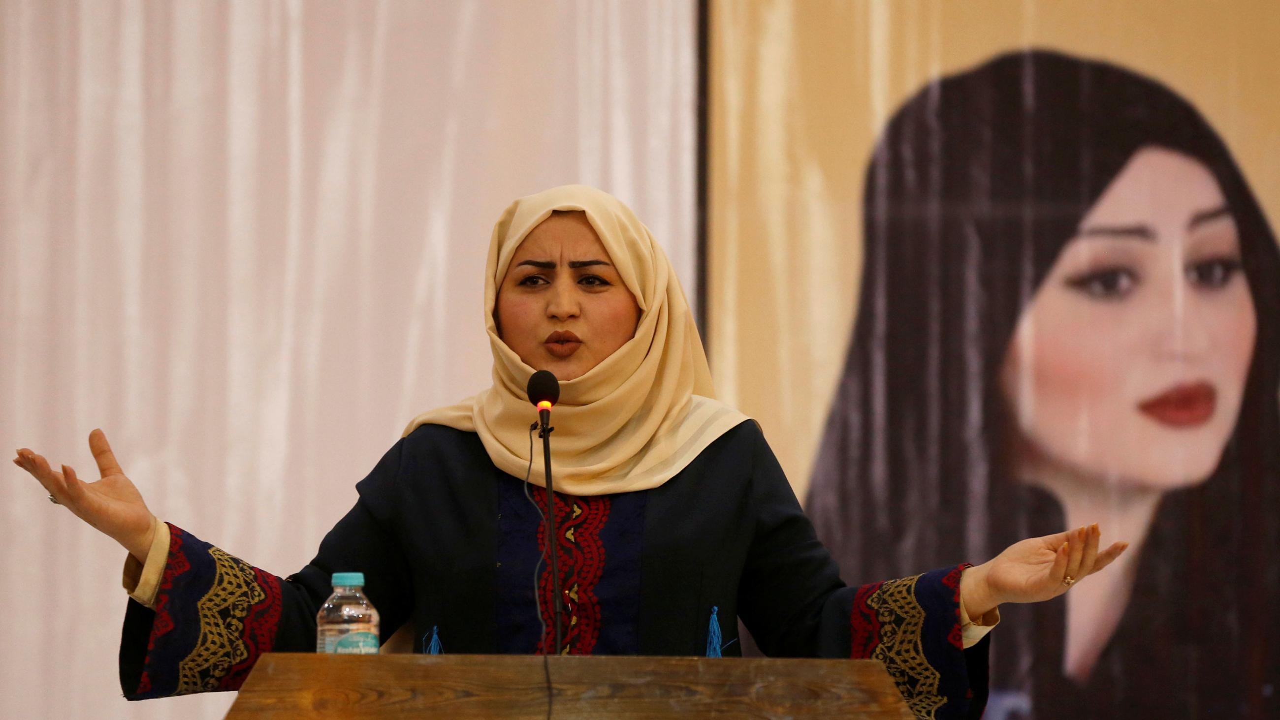 Picture shows the candidate at a podium speaking with a picture of another woman in the background. 