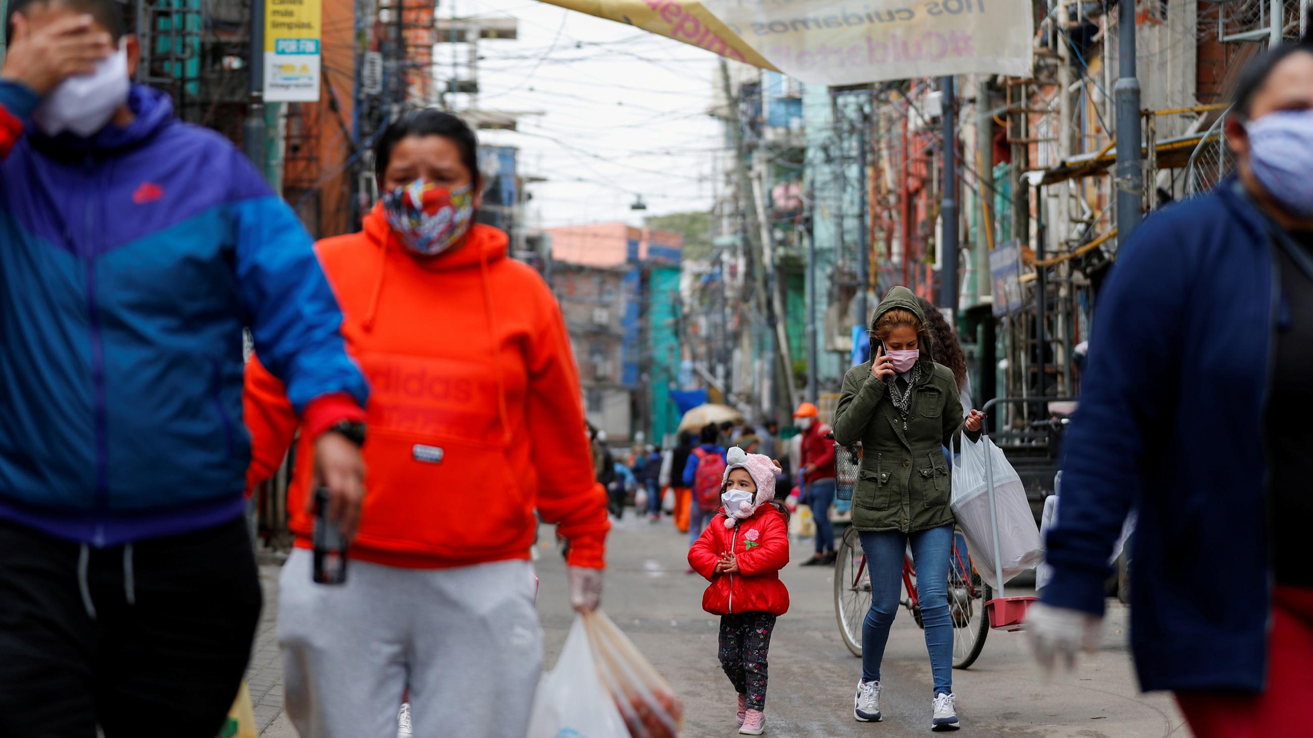 The photo shows a number of people walking up a crowded street. 