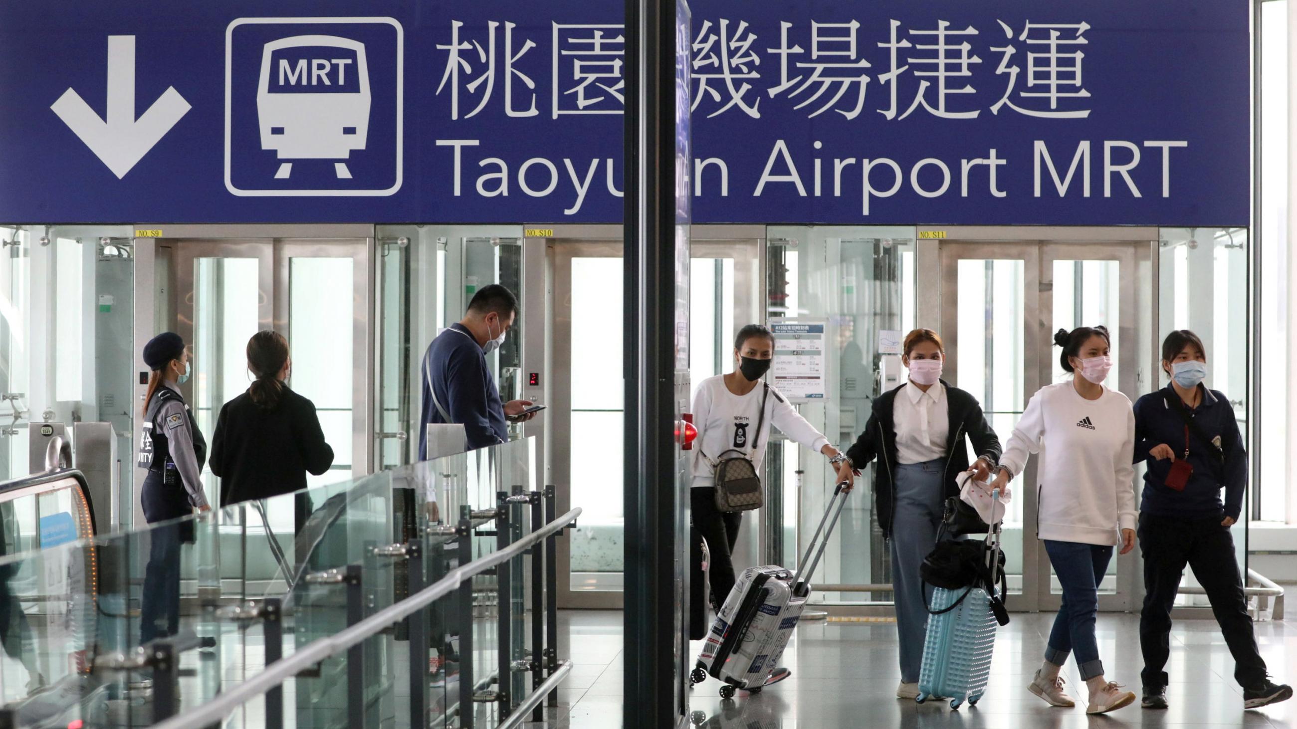 The photo shows people with their luggage walking through a terminal. 