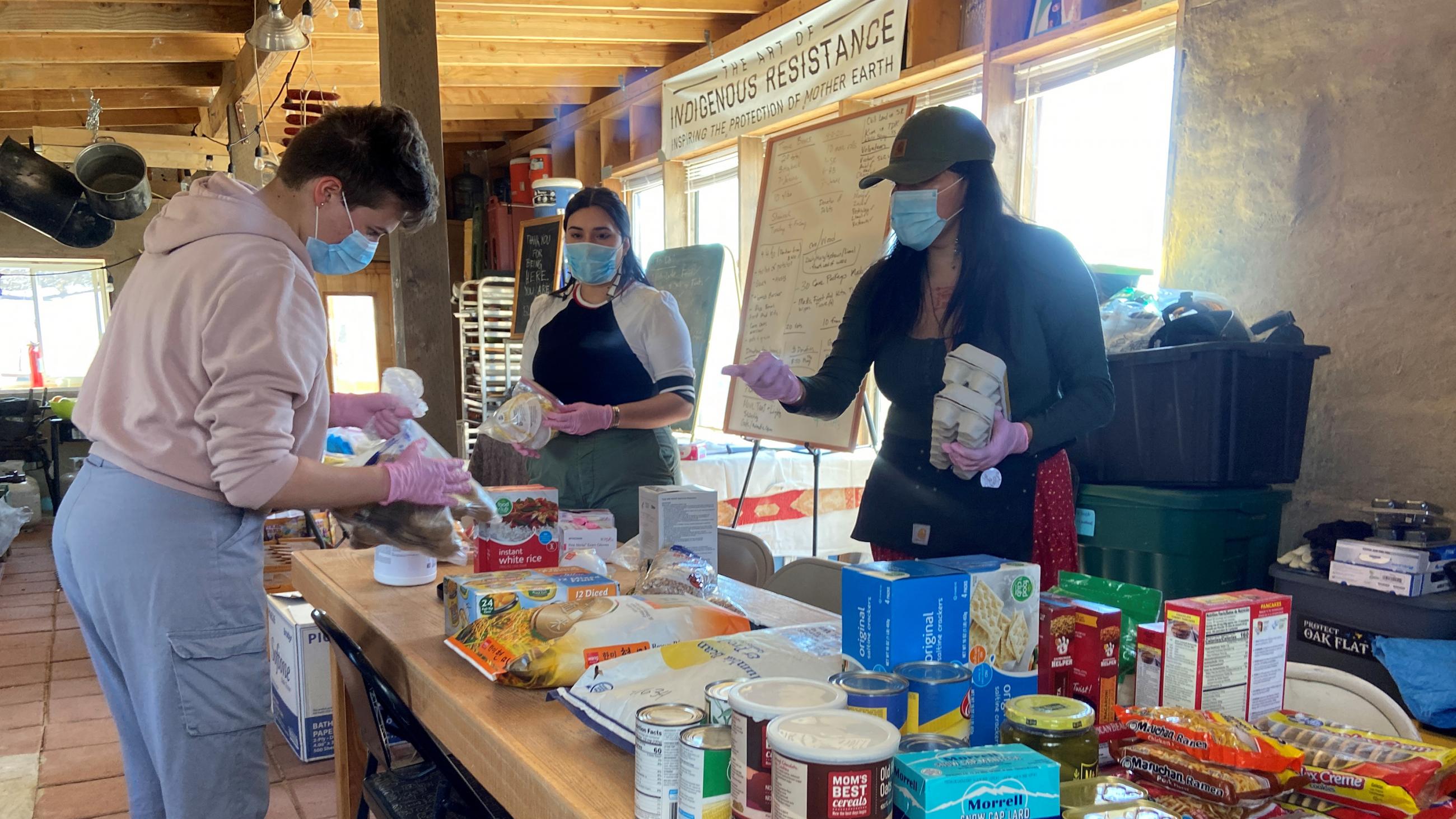 Picture shows several people around a long table overflowing with essential supplies. 