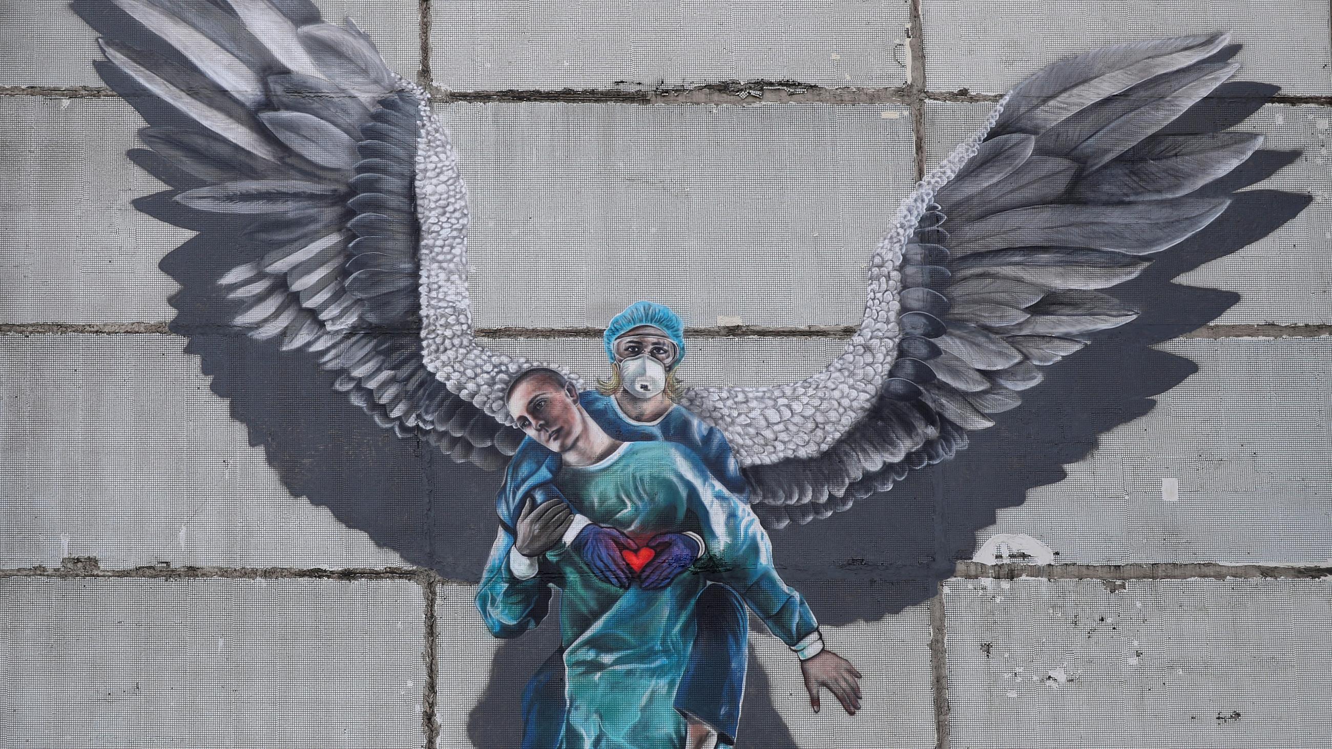 Picture shows a mutal of a health worker with angel's wings lifting another health worker and holding a heart in her hands. 