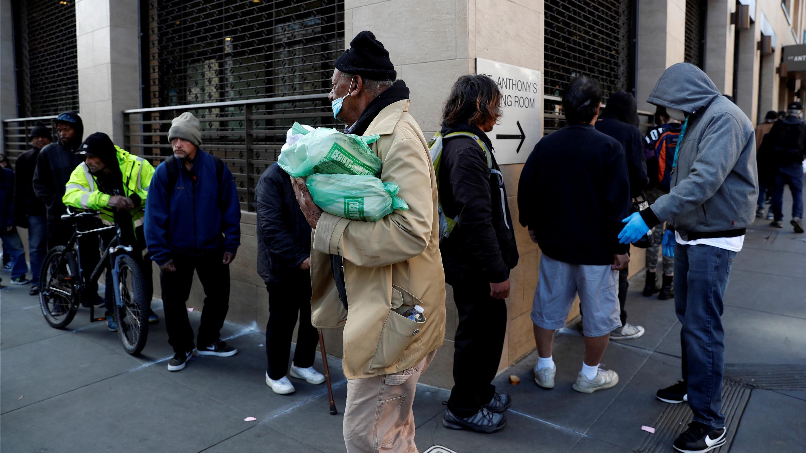 Picture shows a number of people lined up around a corner. 