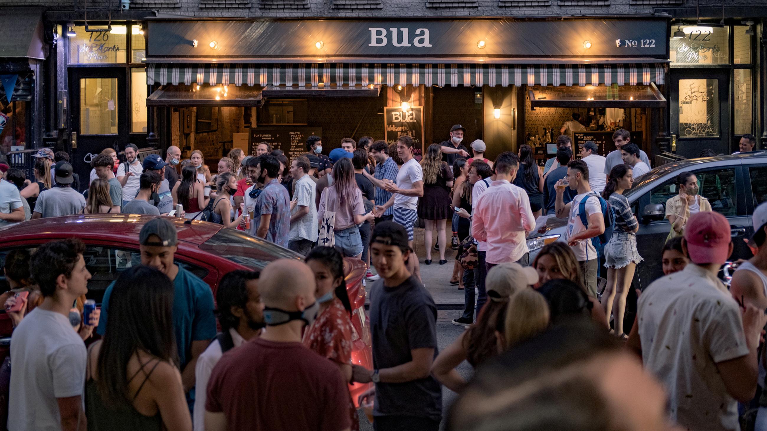 Picture shows a crowd of people standing outside on the street in New York. 