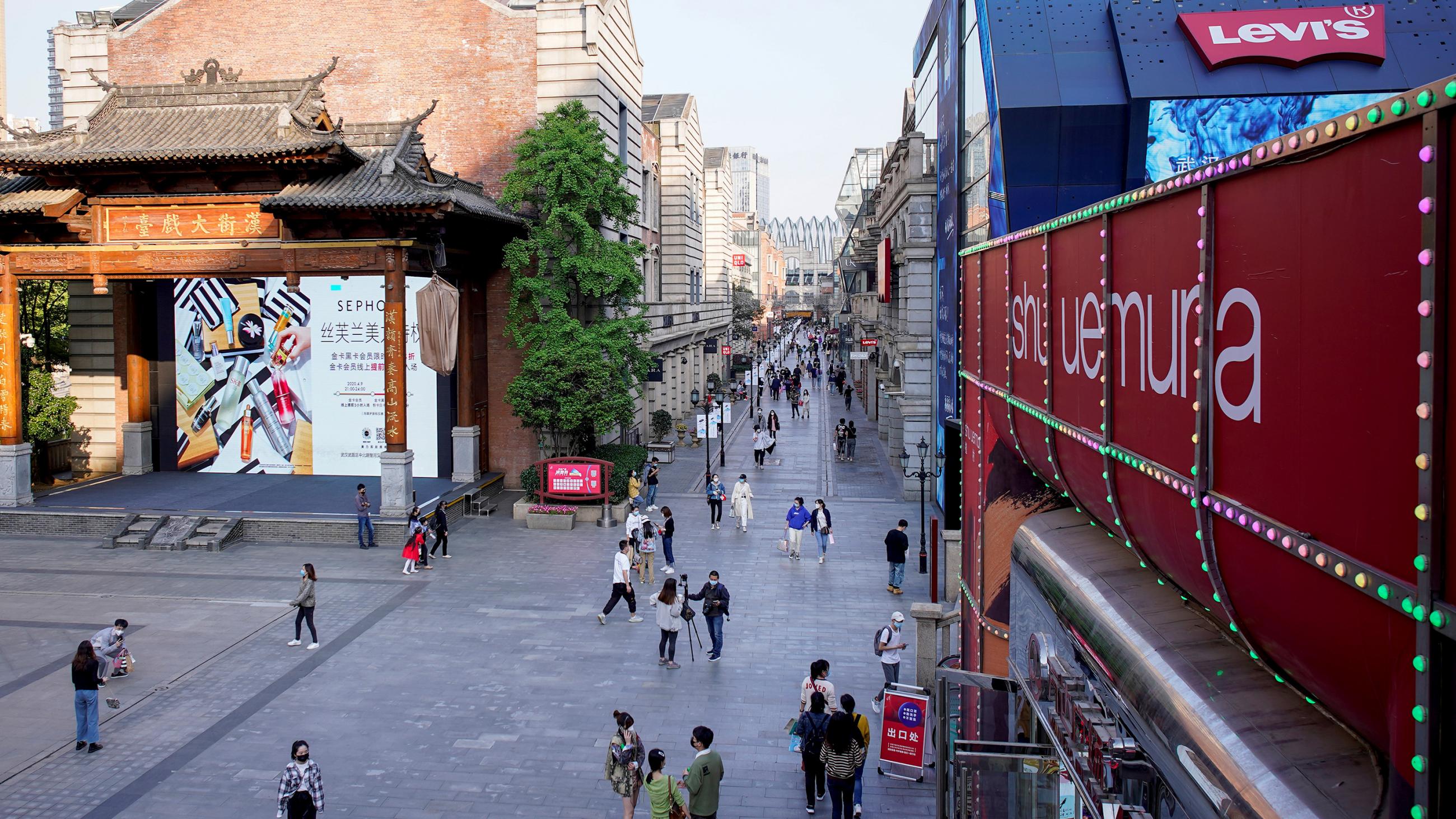 This photo shows a shopping complex in Wuhan, China, on April 9, 2020. The photo shows a street from above sparsely crowded with people. 