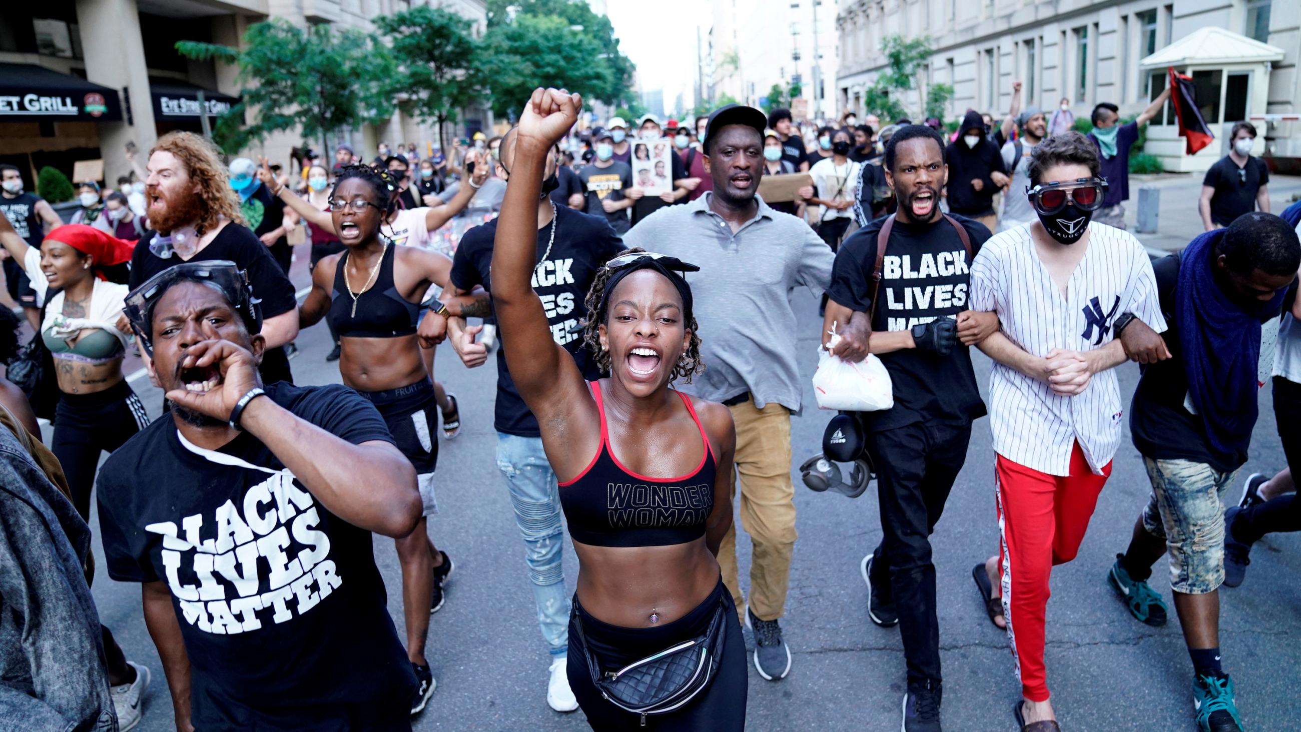 The photo shows a crowd walking down a broad city street. 