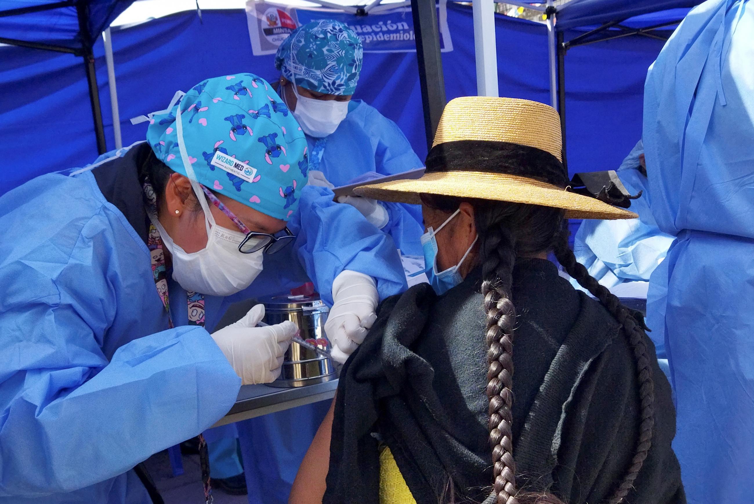 A Peruvian woman receives the AstraZeneca vaccine as authorities begin vaccinating people who make a living crossing the border between Bolivia and Peru, in Desaguadero, Peru May 21, 2021.