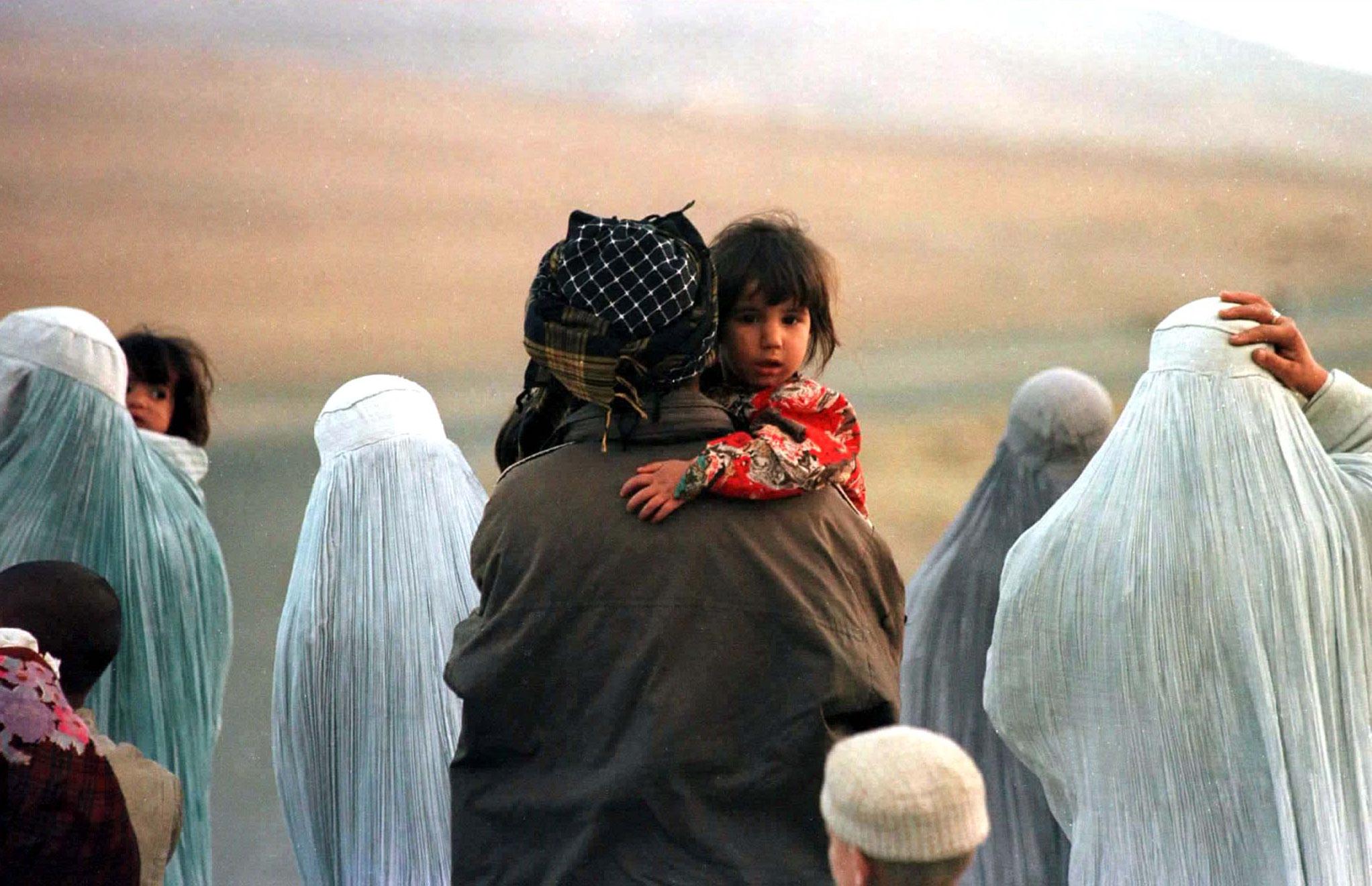 Afghan refugees walk along the road fleeing fighting north of Kabul October 11