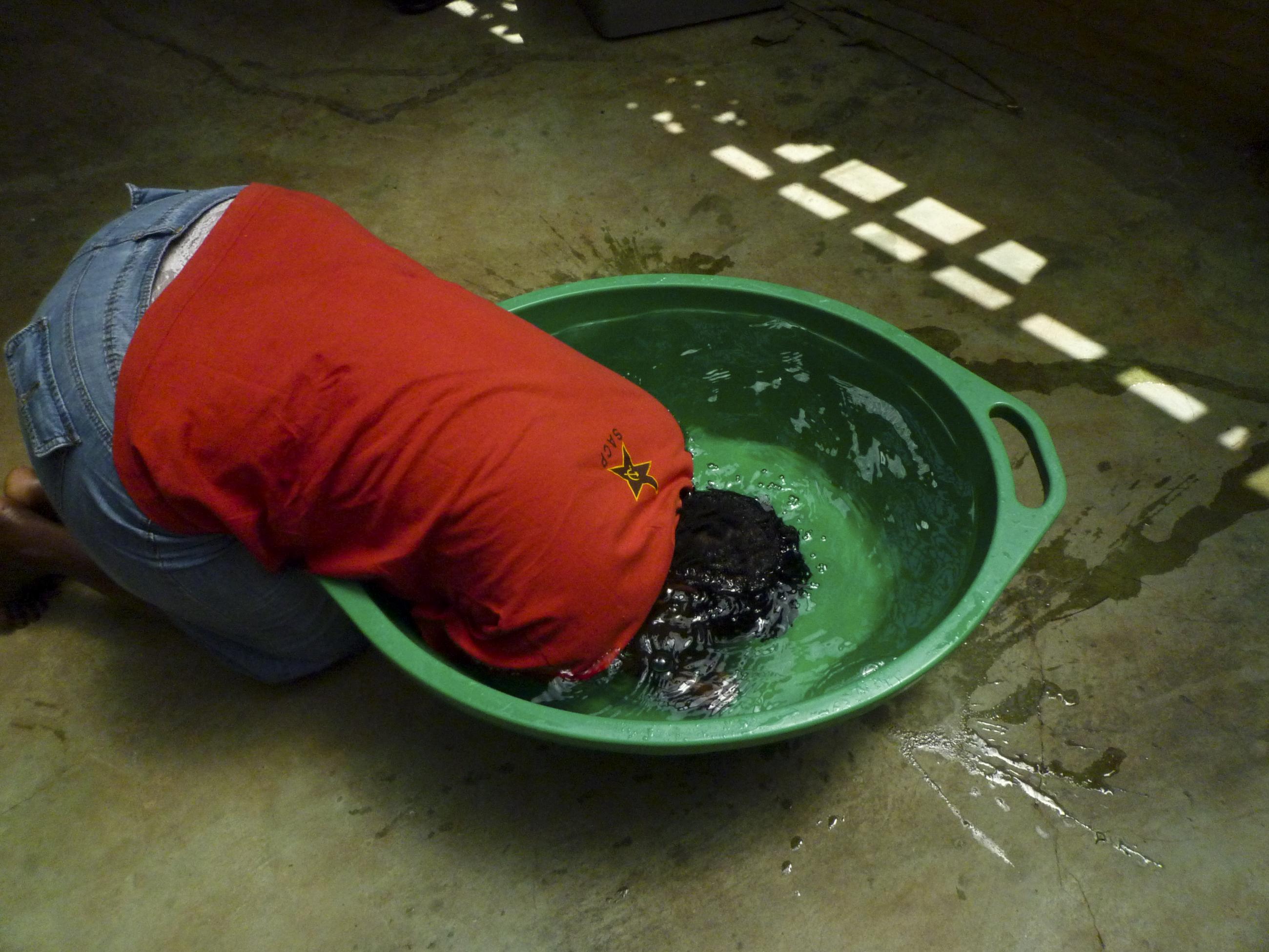 An HIV-positive person bend forward into a large tub of water, submerging their head and arms